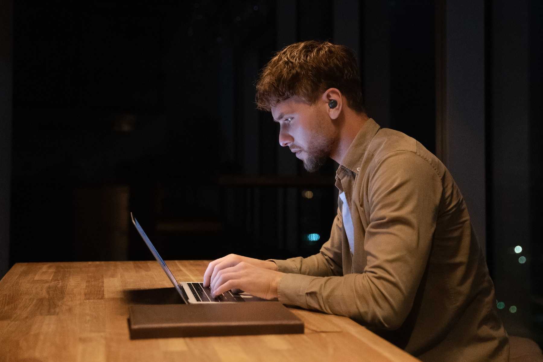 man sitting in a dark room with laptop large