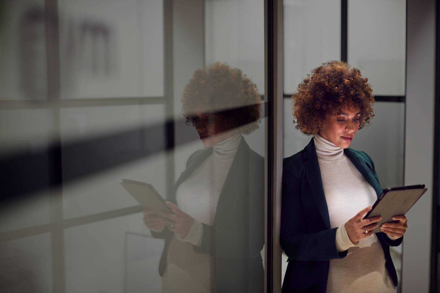 woman in suit looking down on tablet